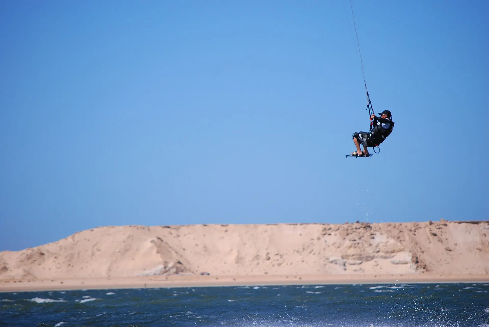 Un kitesurfeur en plein saut au-dessus d'une dune, à Dakhla